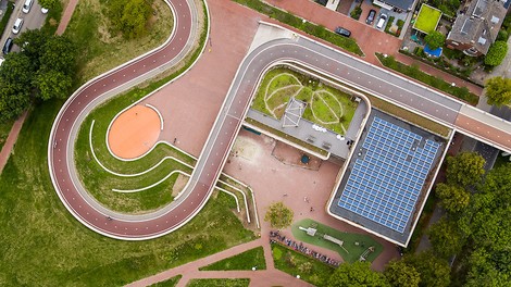 Eine Fahrradbrücke, die zwei Stadtteile miteinander verbindet und in die eine Schule eingebaut ist.